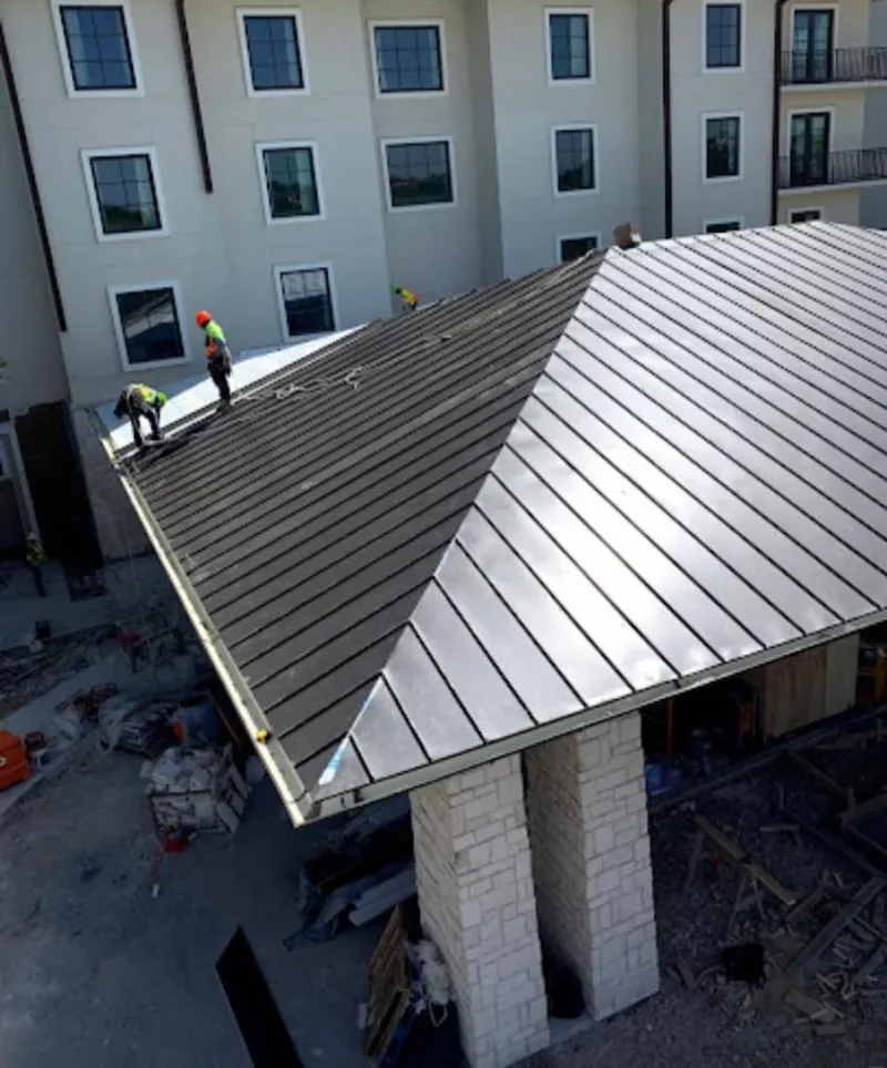 Crew installing standing seam metal roof panels on a commercial project in Warrenton